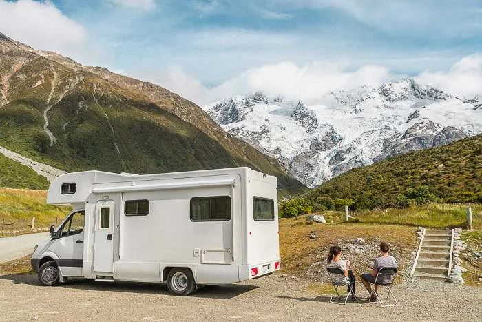 two people sitting outside a self contained campervan NZ with a view of Aoraki Mount Cook